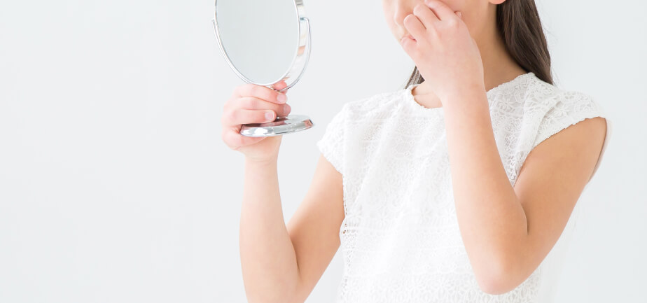 イメージ画像・コンタクトレンズが目の裏に入ってしまい、鏡を見る女性